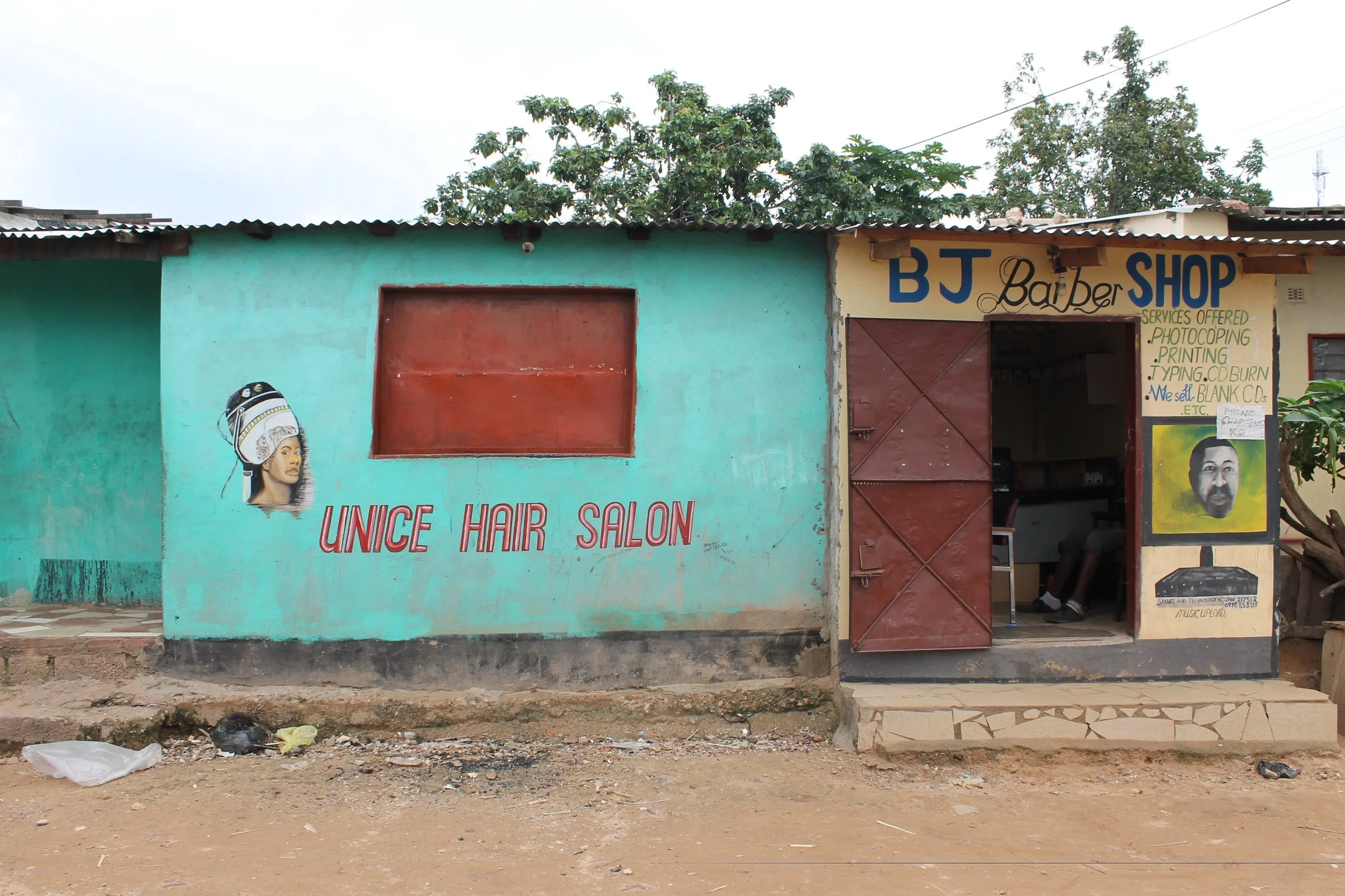 The middle and end shops outside Emeli's house, one rented out and one run by Emeli's son to prepare him to be a businessman in his community. 