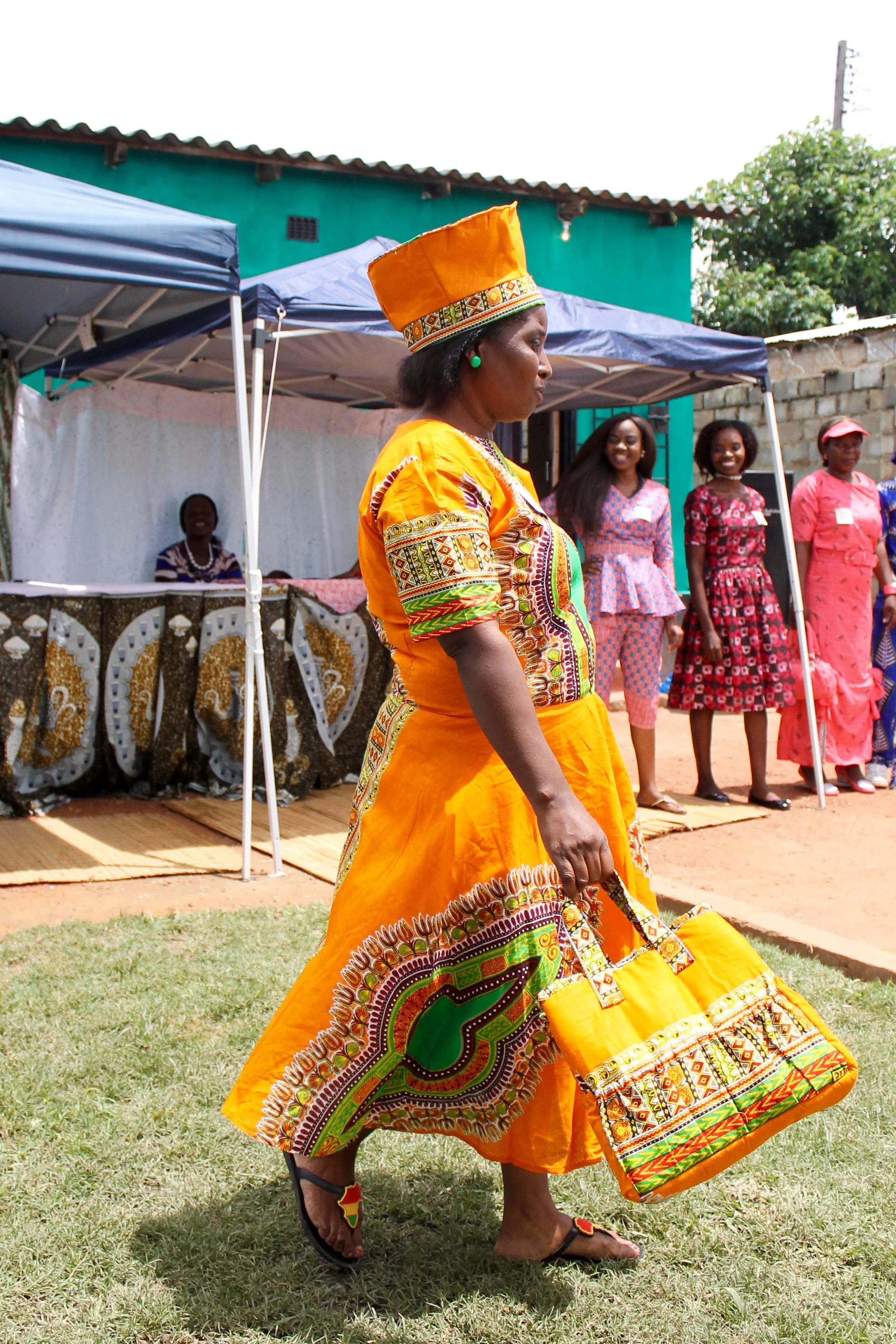 Gladys' head-to-toe ensemble gets quite the reaction from the crowd. Matching purse, a-line dress, and traditional hat in a beautiful traditional chitenge fabric. 