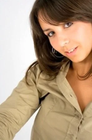 Photo of young woman with shoulder length brown hair wearing a tan colour shirt