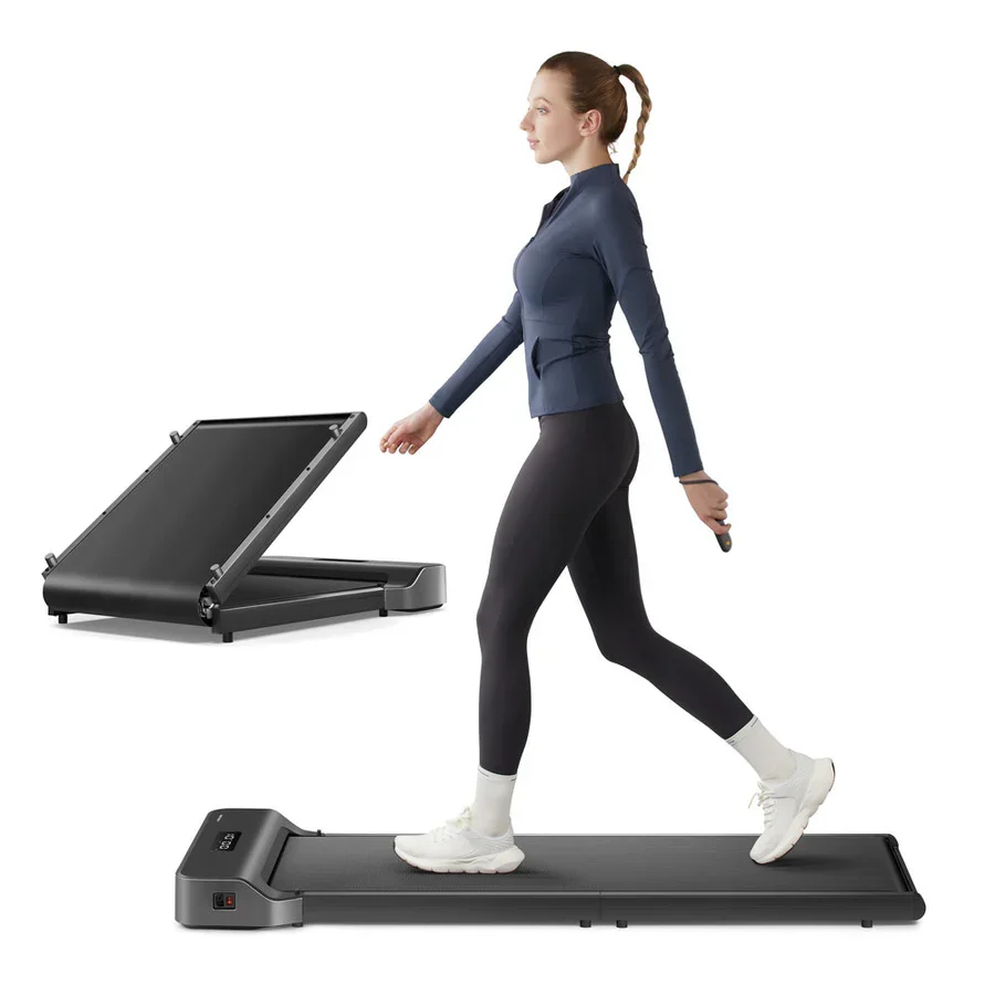 Computer-generated image of a woman in sports clothing walking on the black walking pad. An inset image shows the walking pad partly folded. There is no background detail and everything else is white.
