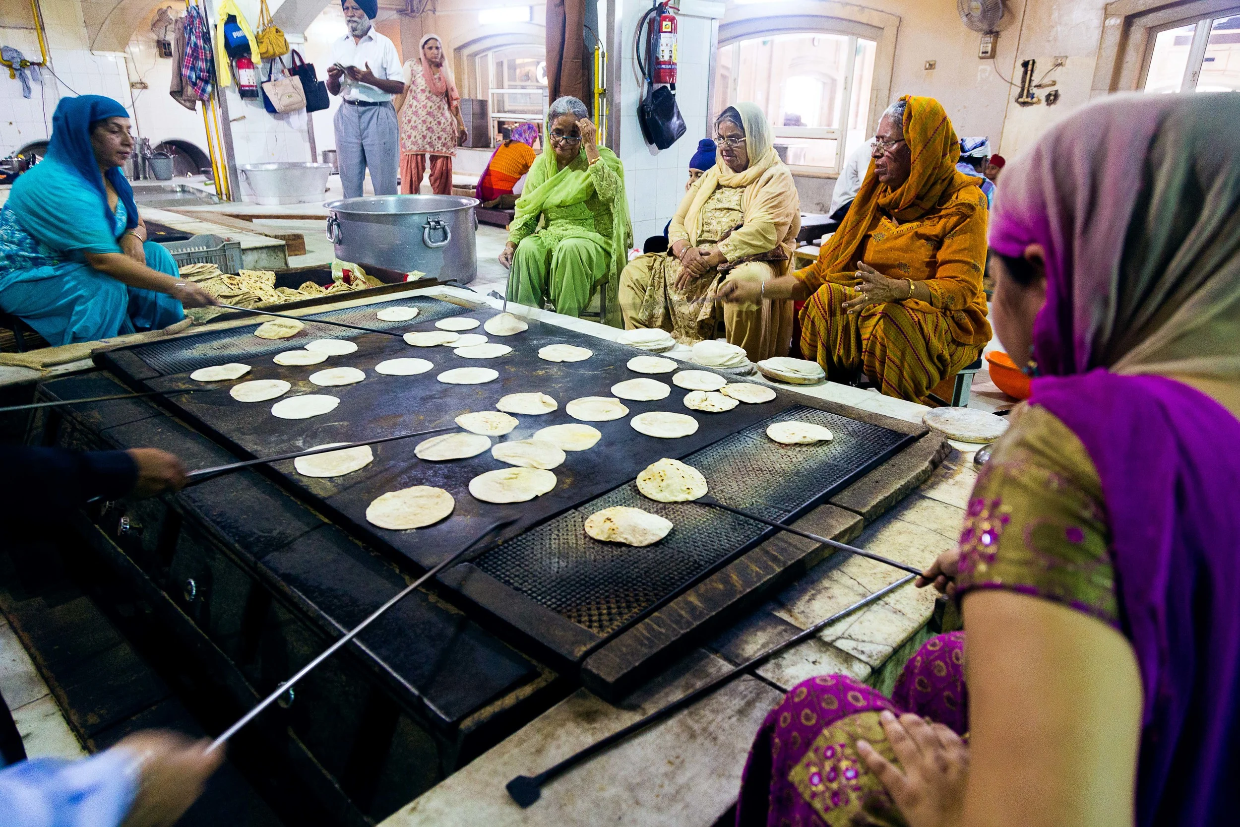 A group of women cook and flip chapati that will be used to feed the hungry. These women are just a few of the volunteers that help feed over 10,000 poor and homeless people a day at the Sikh Temple Gurudwara Bangla Sahib in New Delhi, India.