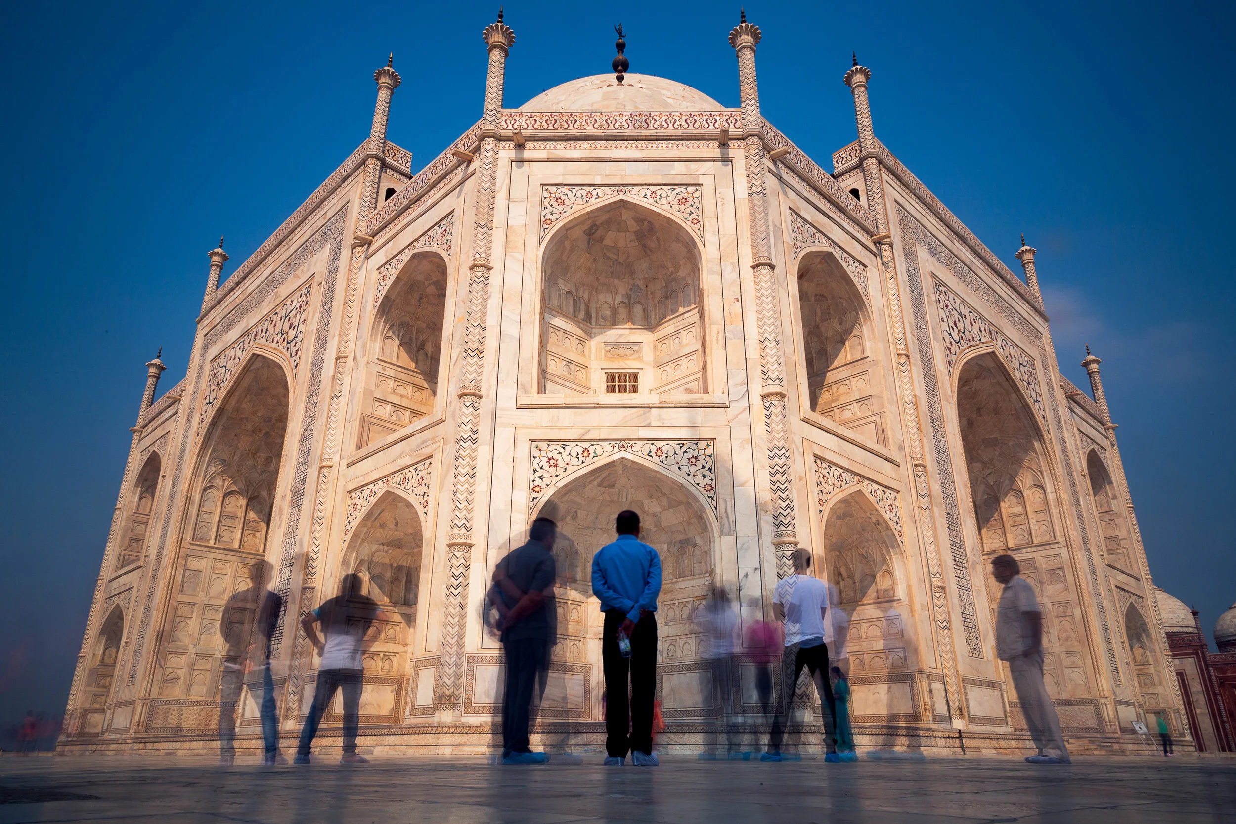 A man stands in admiration of the Taj Mahal as others come and go.