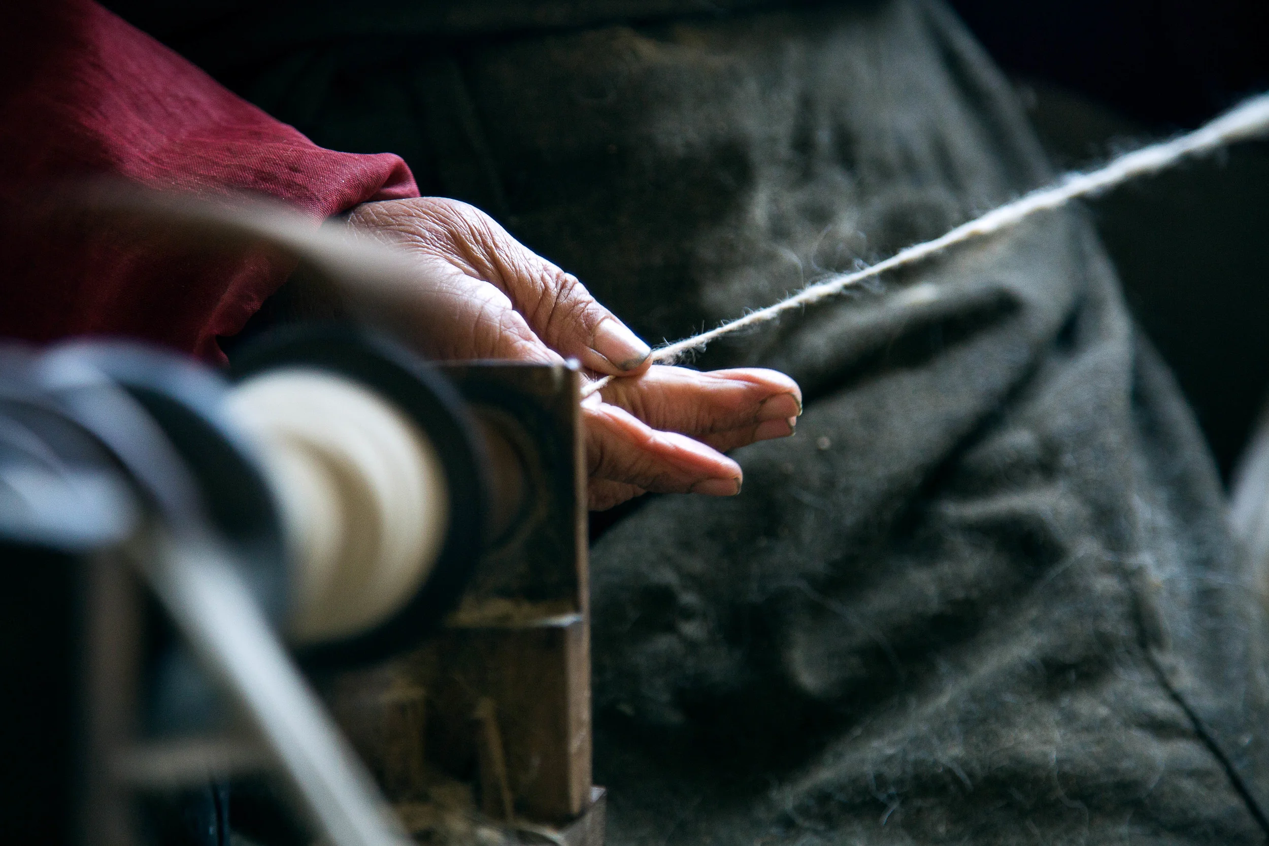A women turning sheep wool into yarn at the Tibet Relief Center in Darjeerling, India.