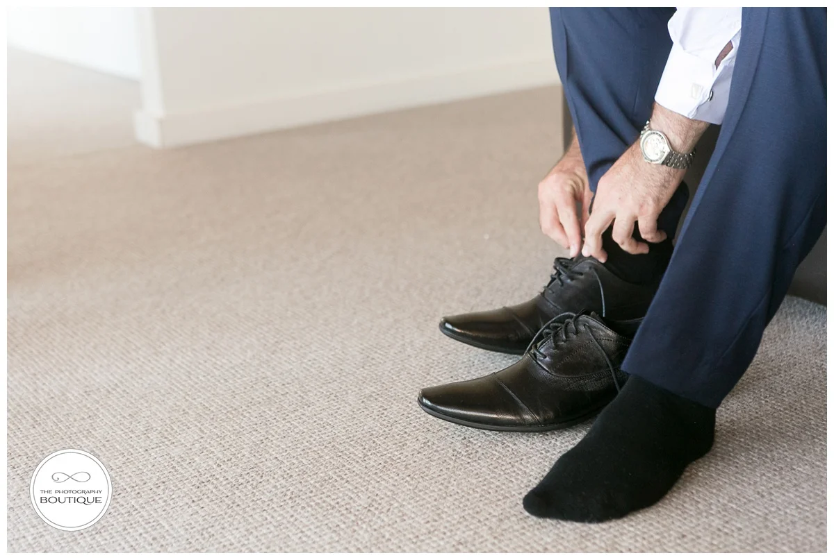 groom putting on wedding shoes