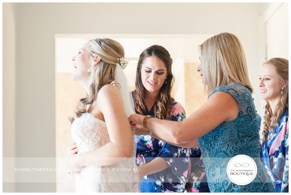 mum helping bride put wedding dress on