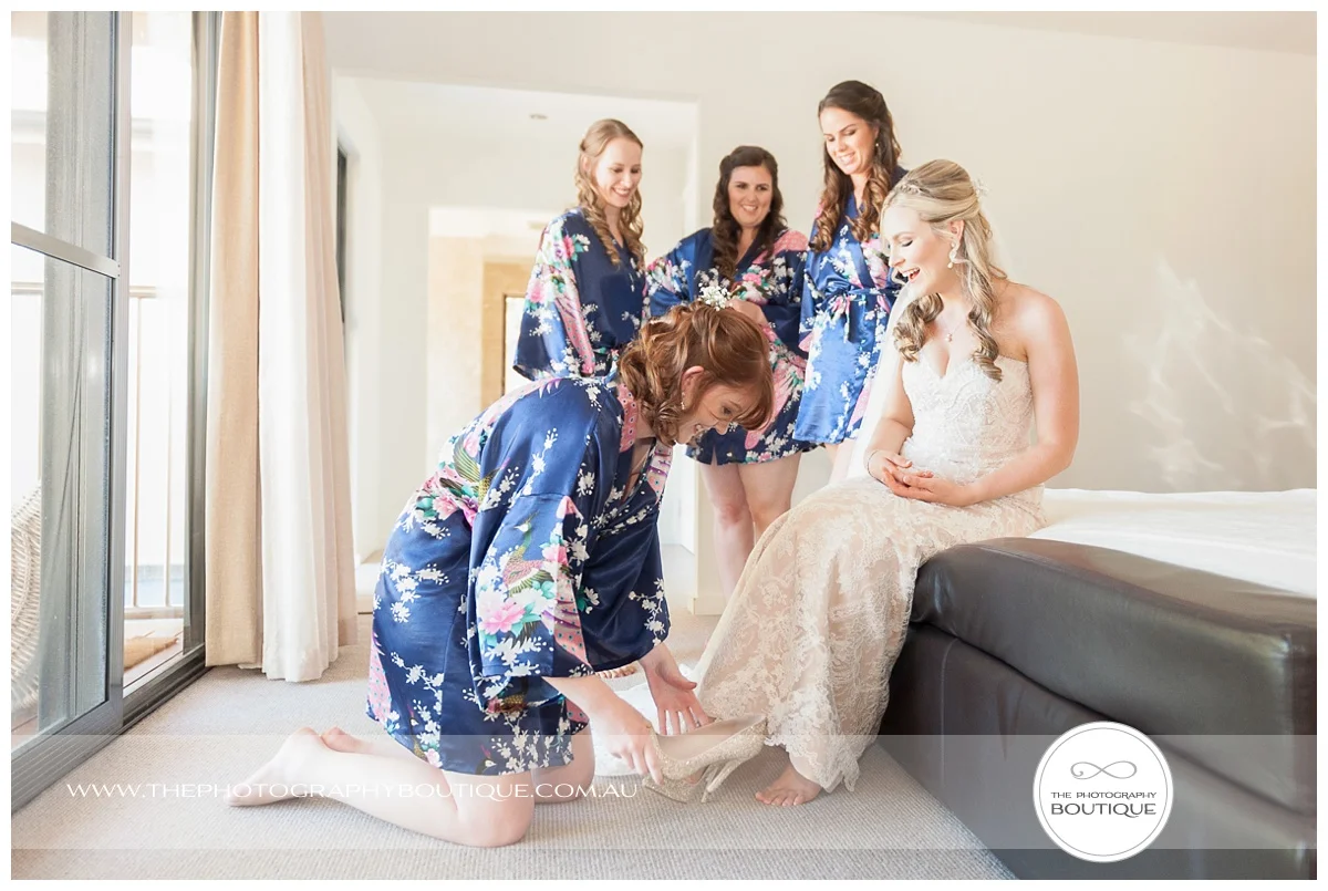 bridesmaids putting brides shoes on