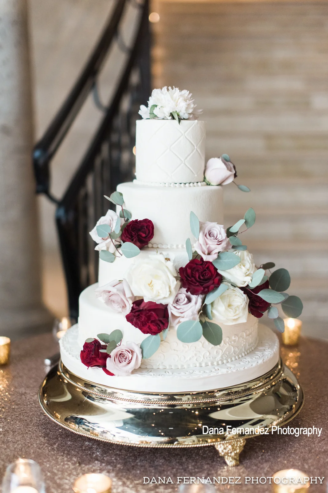 A 4 tiered white wedding cake with multi colored flowers