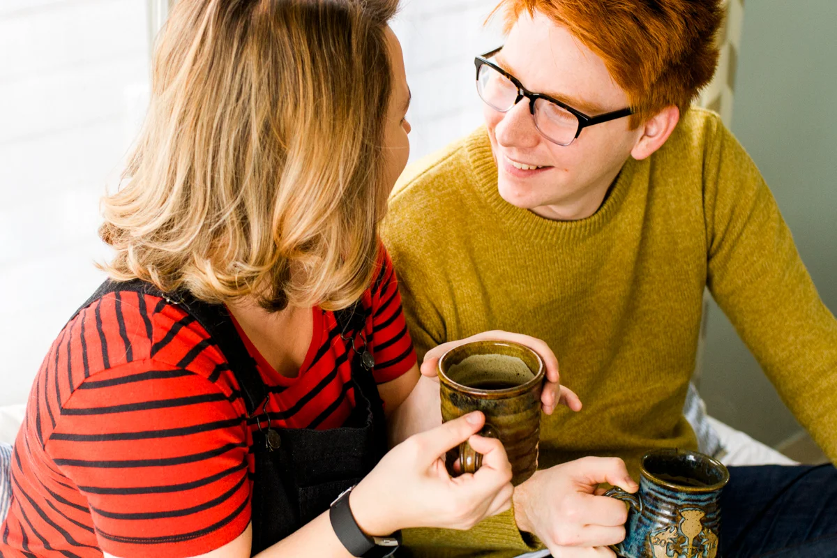 Smiling together over coffee during an intimate in-home couples session in kansas city, MO