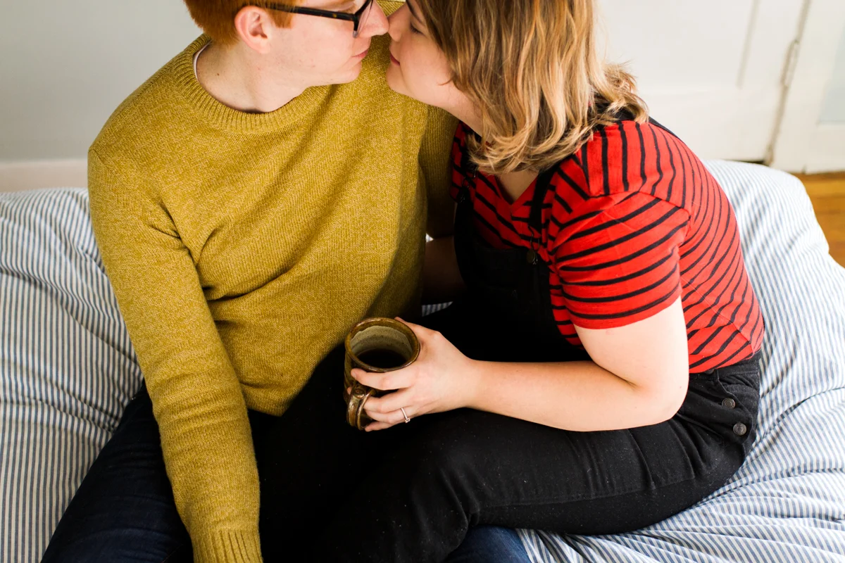cuddling together with coffee on a bed during an intimate in-home couples session in Kansas City, MO