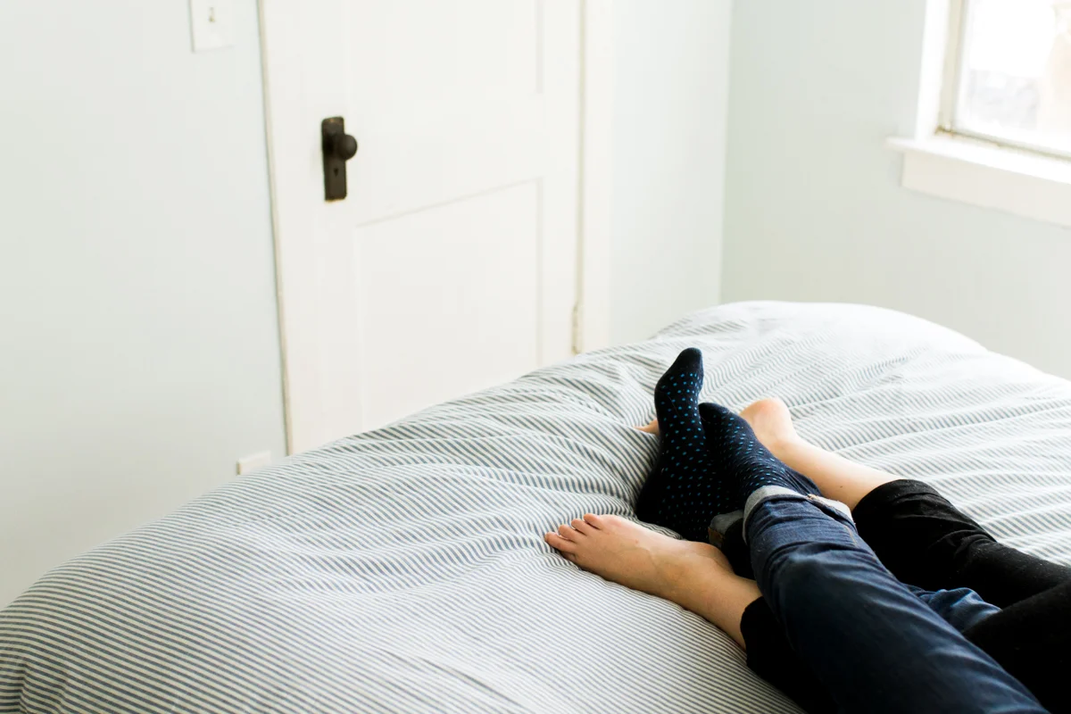 cuddling together on a bed during an intimate in-home couples session in Kansas City, MO