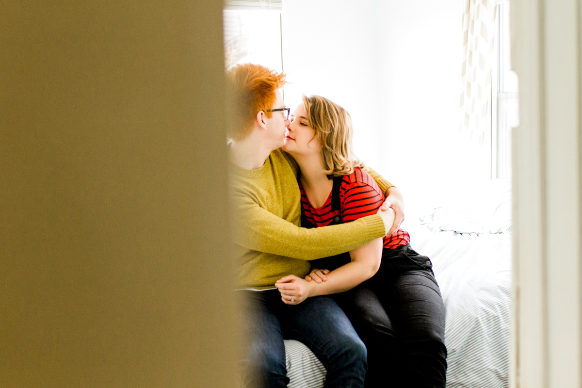 cuddling together on a bed during an intimate in-home couples session in Kansas City, MO