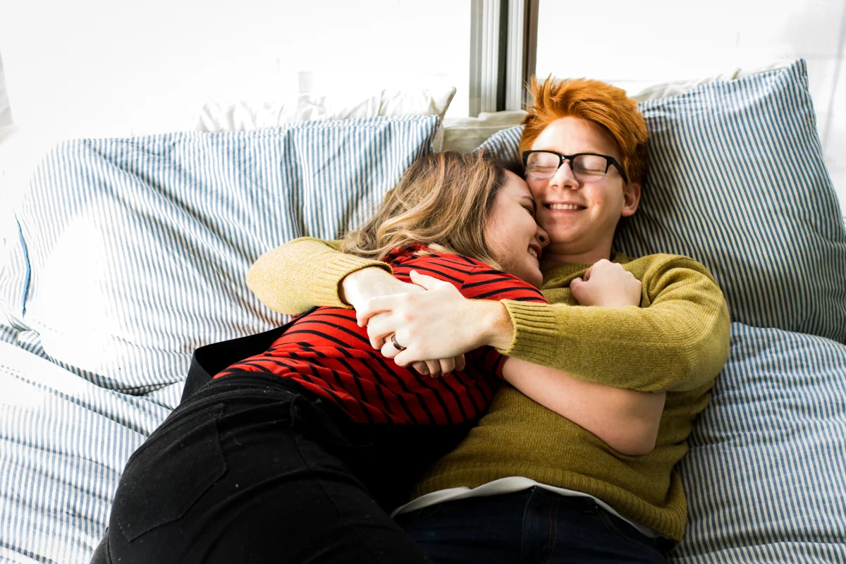 cuddling together on a bed during an intimate in-home couples session in Kansas City, MO