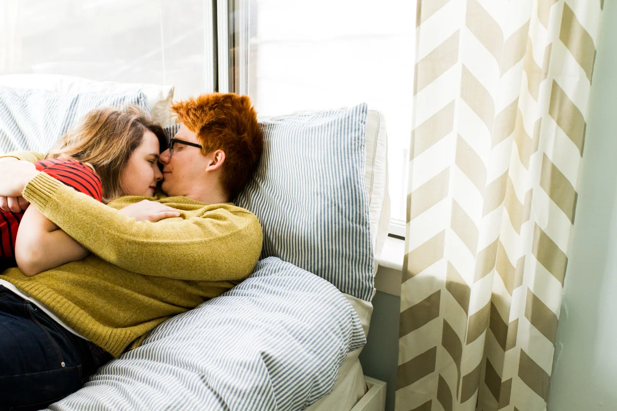 cuddling together on a bed during an intimate in-home couples session in Kansas City, MO