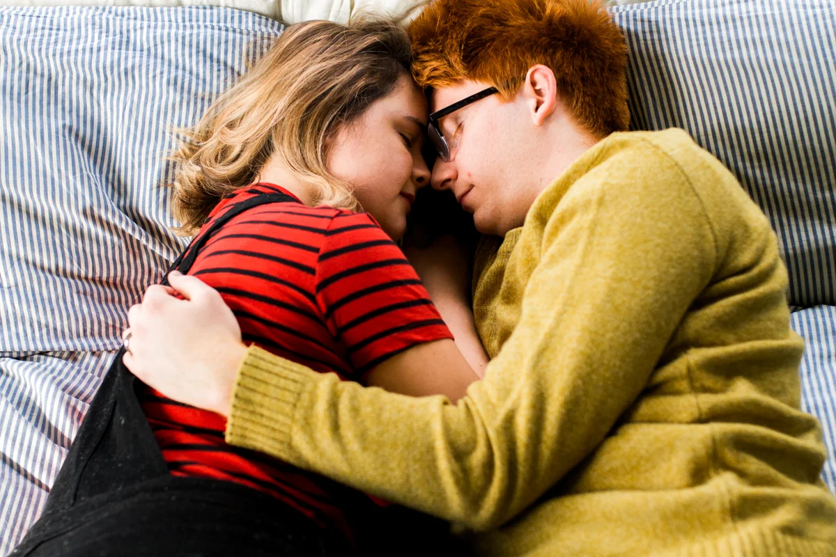 cuddling together on a bed during an intimate in-home couples session in Kansas City, MO