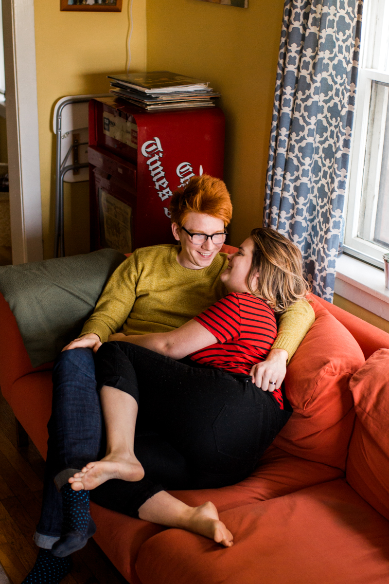  laughing together on a couch in an intimate in-home couples session in Kansas City, MO 