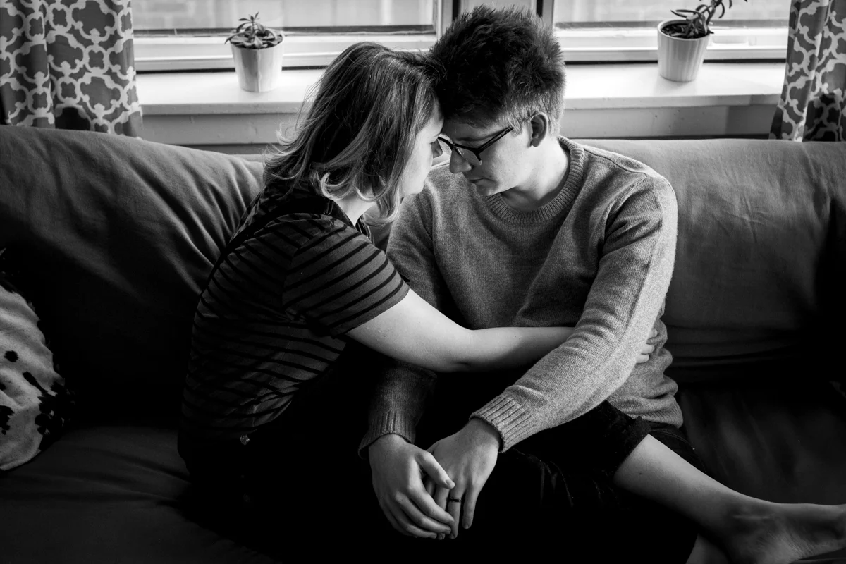 black and white photo of a couple cuddling together on a couch during an intimate in-home couples session in Kansas City, MO