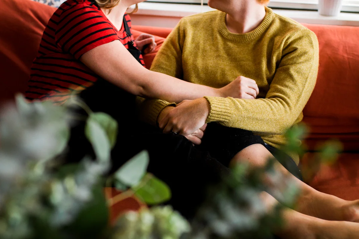 cuddling together on a couch during an intimate in-home couples session in Kasnas City, MO