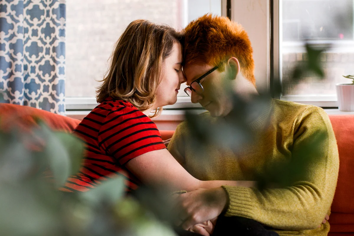 cuddling together on a couch during an intimate in-home couples session in Kasnas City, MO