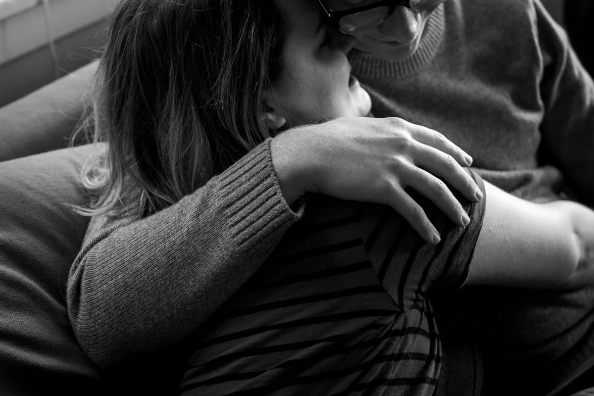 black and white photo of a couple cuddling together on a couch during an intimate in-home couples session in Kasnas City, MO