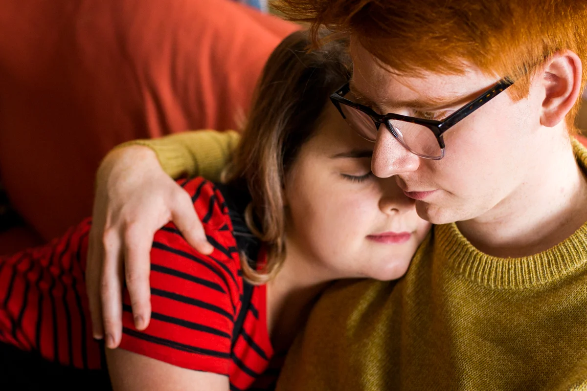 cuddling together on a couch during an intimate in-home couples session in Kasnas City, MO