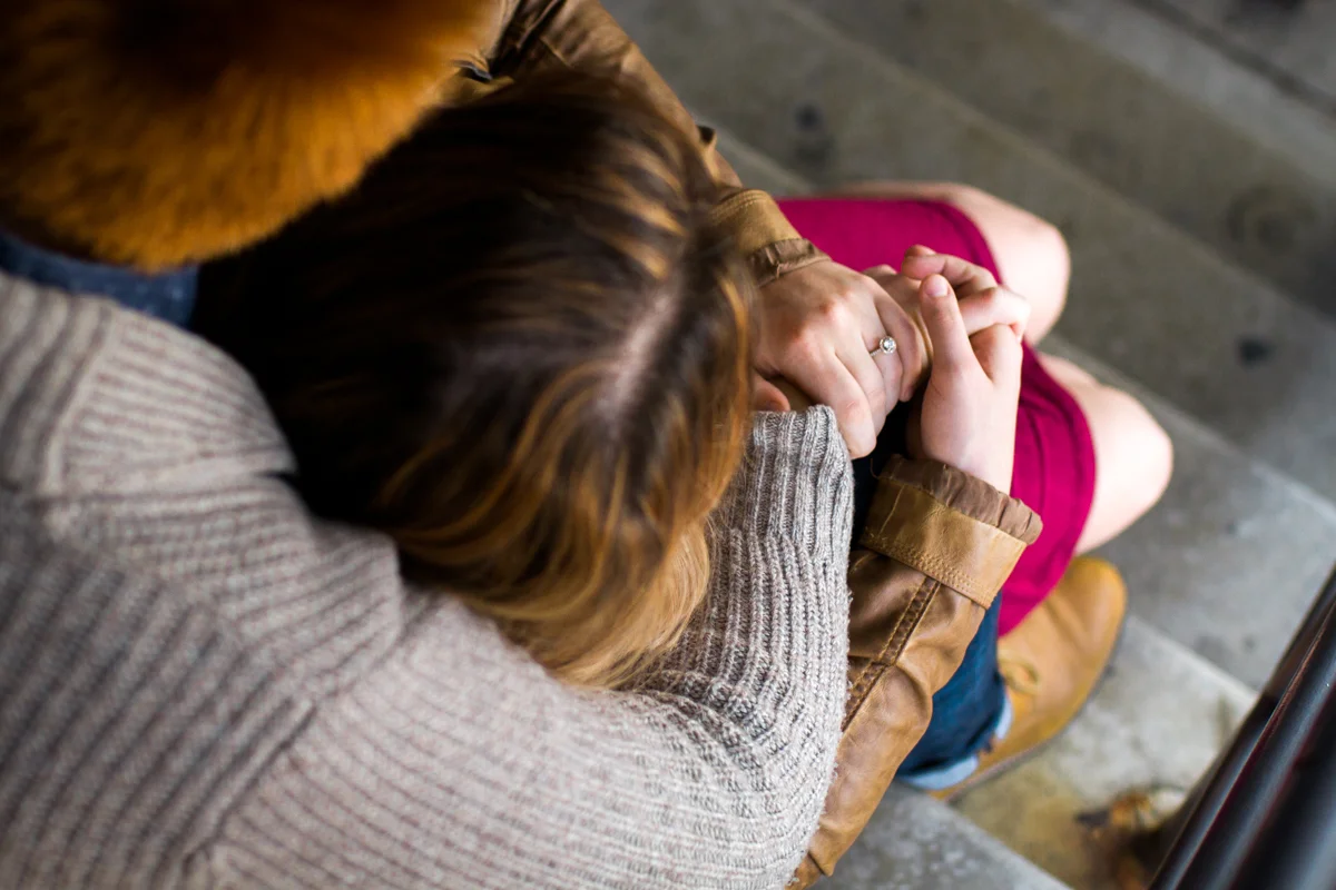 engaged or married couple cuddle in a parking garage in Westport Kansas City, MO engagement ring