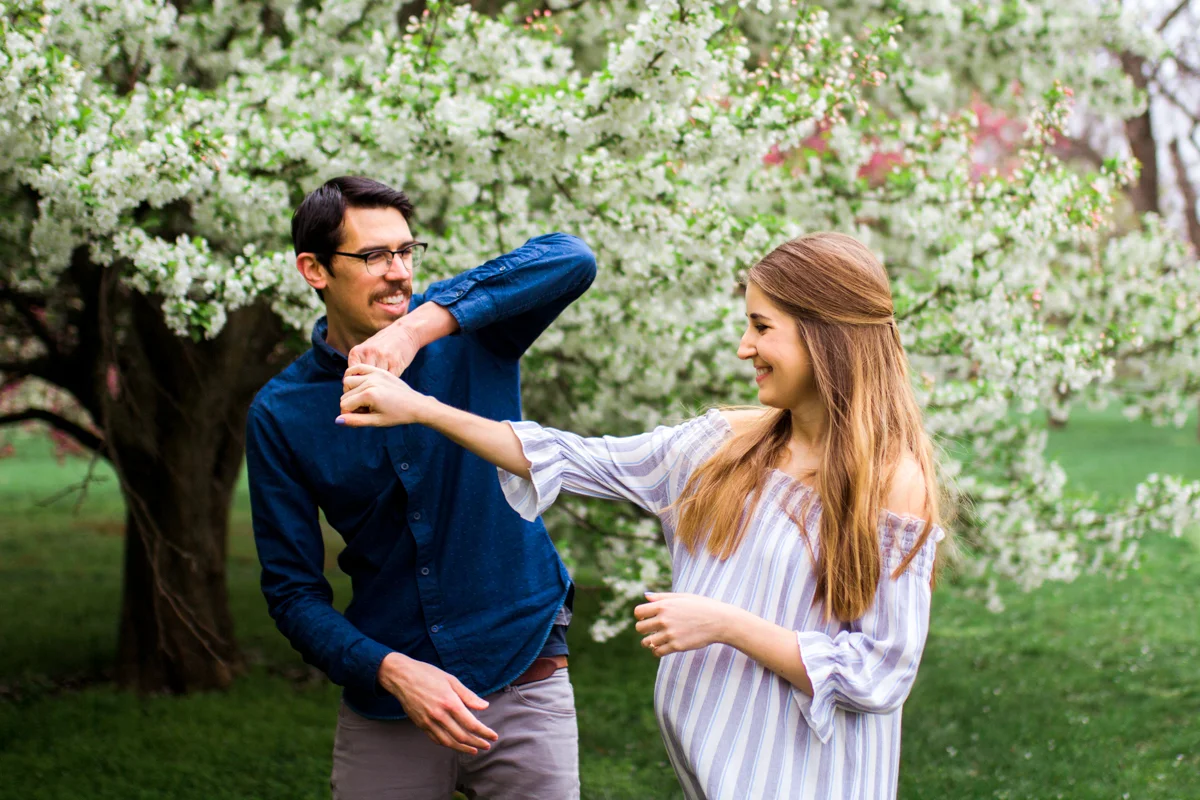Kansas City Loose Park spring maternity session dancing by the flowering apple tree Kansas City maternity photographer