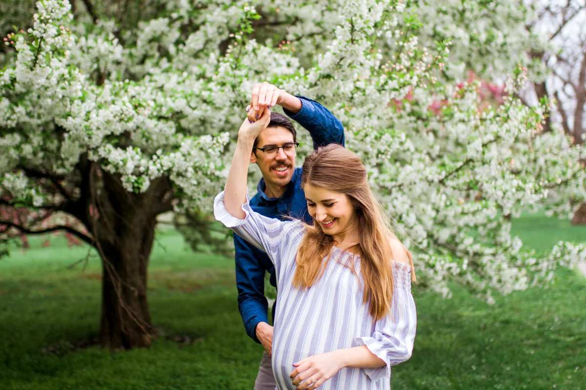 Kansas City Loose Park spring maternity session dancing by the flowering apple tree Kansas City maternity photographer