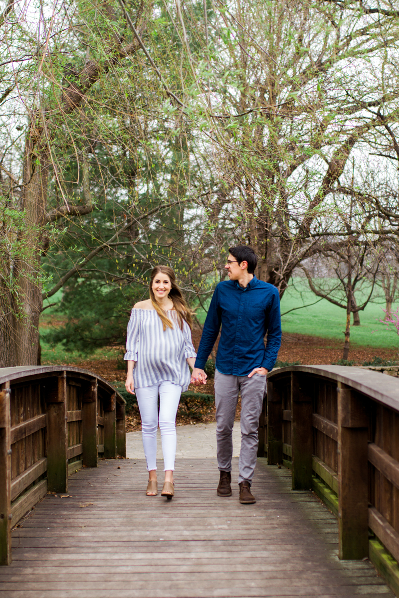  Kansas City Loose Park spring maternity session walking across the bridge holding hands Kansas City maternity photographer 