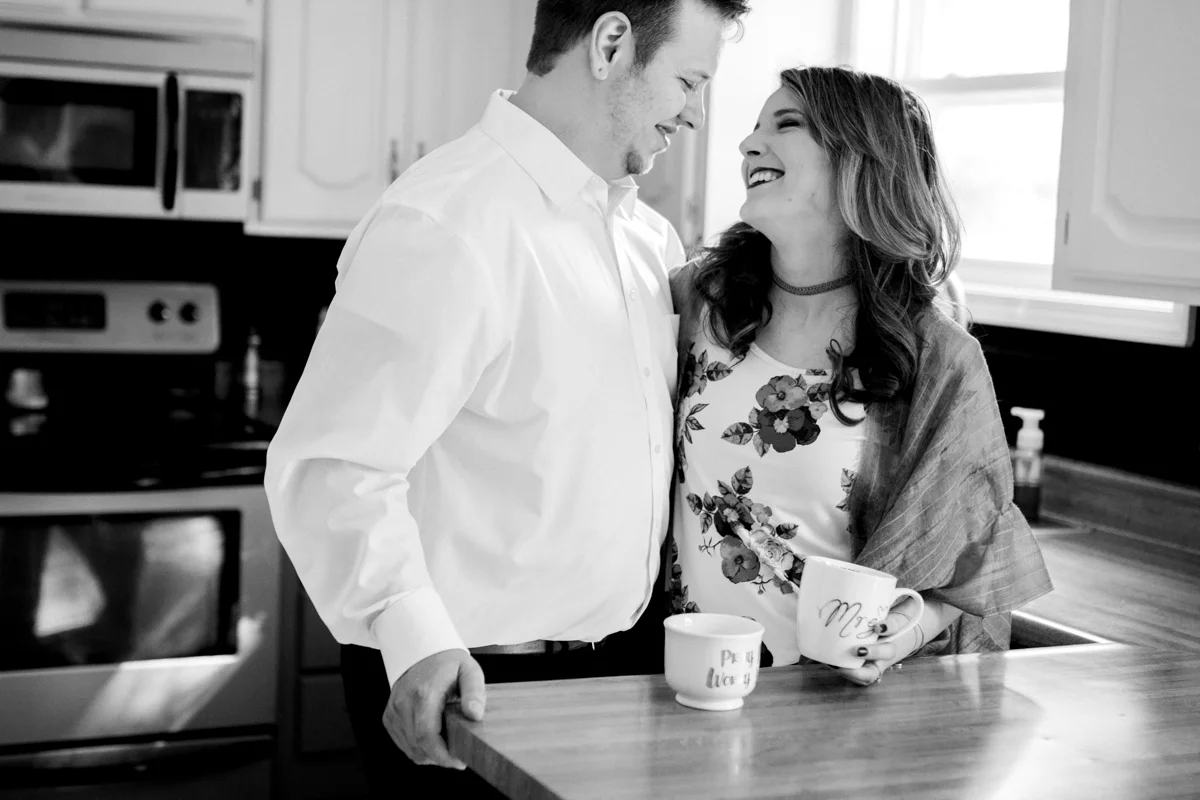 Kansas City lifestyle photographer in home couples session cuddling in the kitchen with coffee engagement photos black and white photo