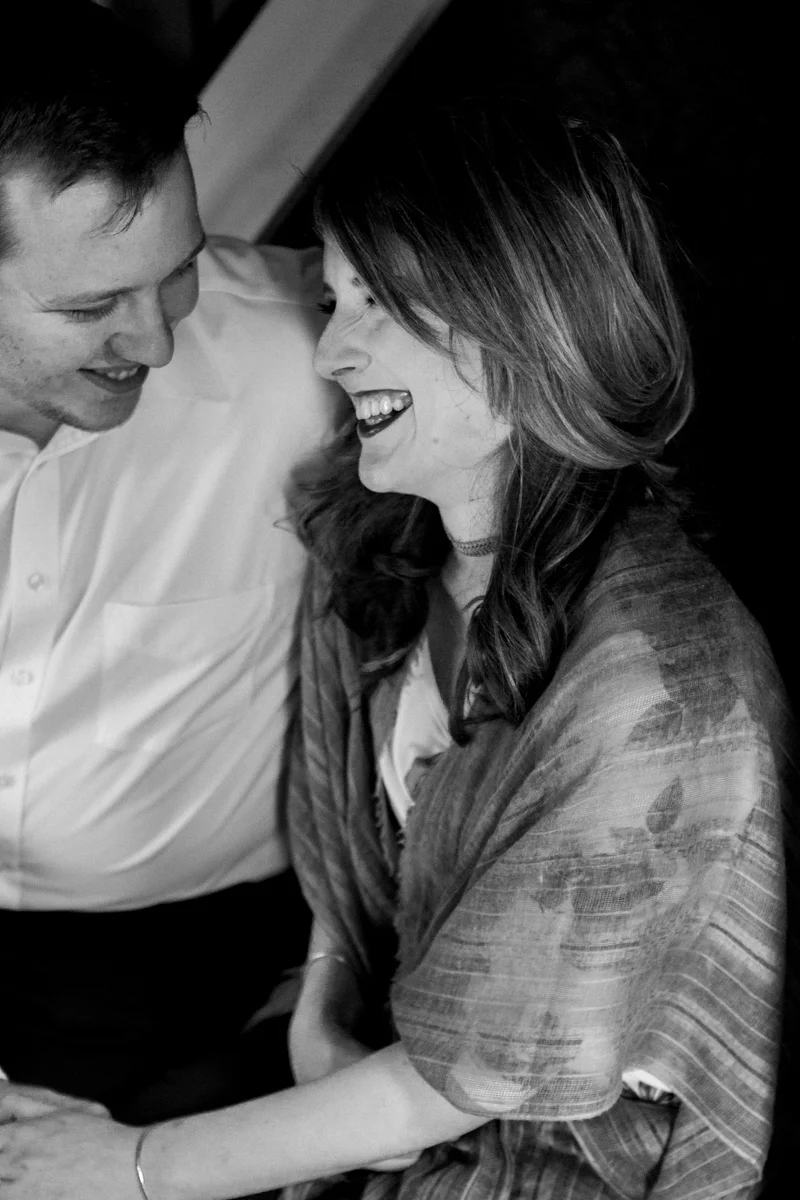 Kansas City lifestyle photographer in home couples session cuddling and laughing on the stairs engagement photos black and white photo
