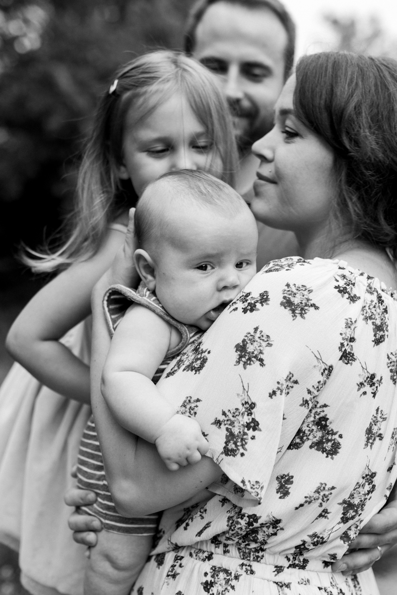  Rebecca Clair Photography Kansas City MO lifestyle family photographer Line Creek Trail Family Session close up of family together and sisters kissing her brother's head black and white photo 