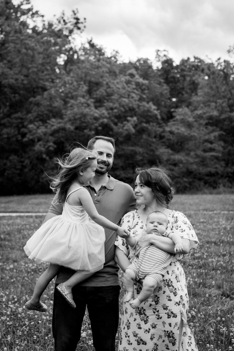  Rebecca Clair Photography Kansas City MO lifestyle family photographer Line Creek Trail Family Session family holding hands under stormy skies black and white photo 