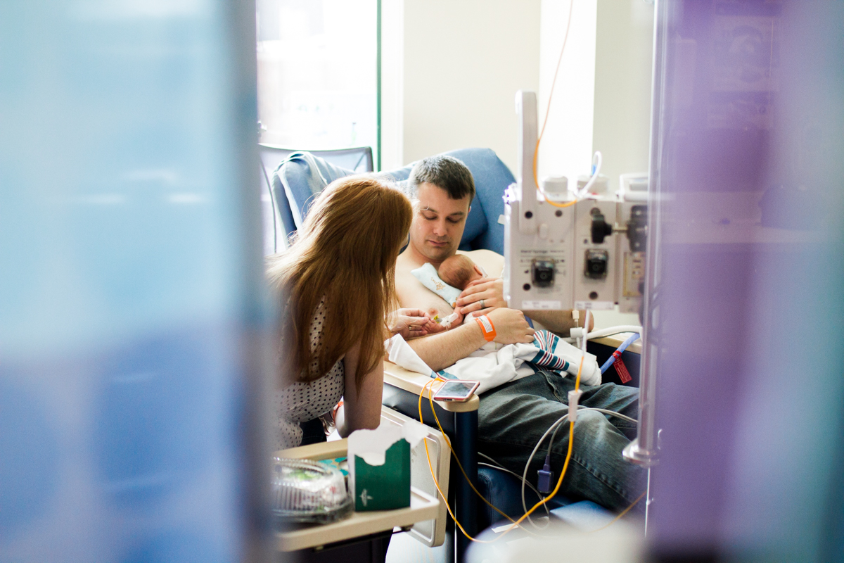 Rebecca Clair Photography lifestyle NICU newborn photography Children's Mercy Hospital mother and father holding baby through the curtains
