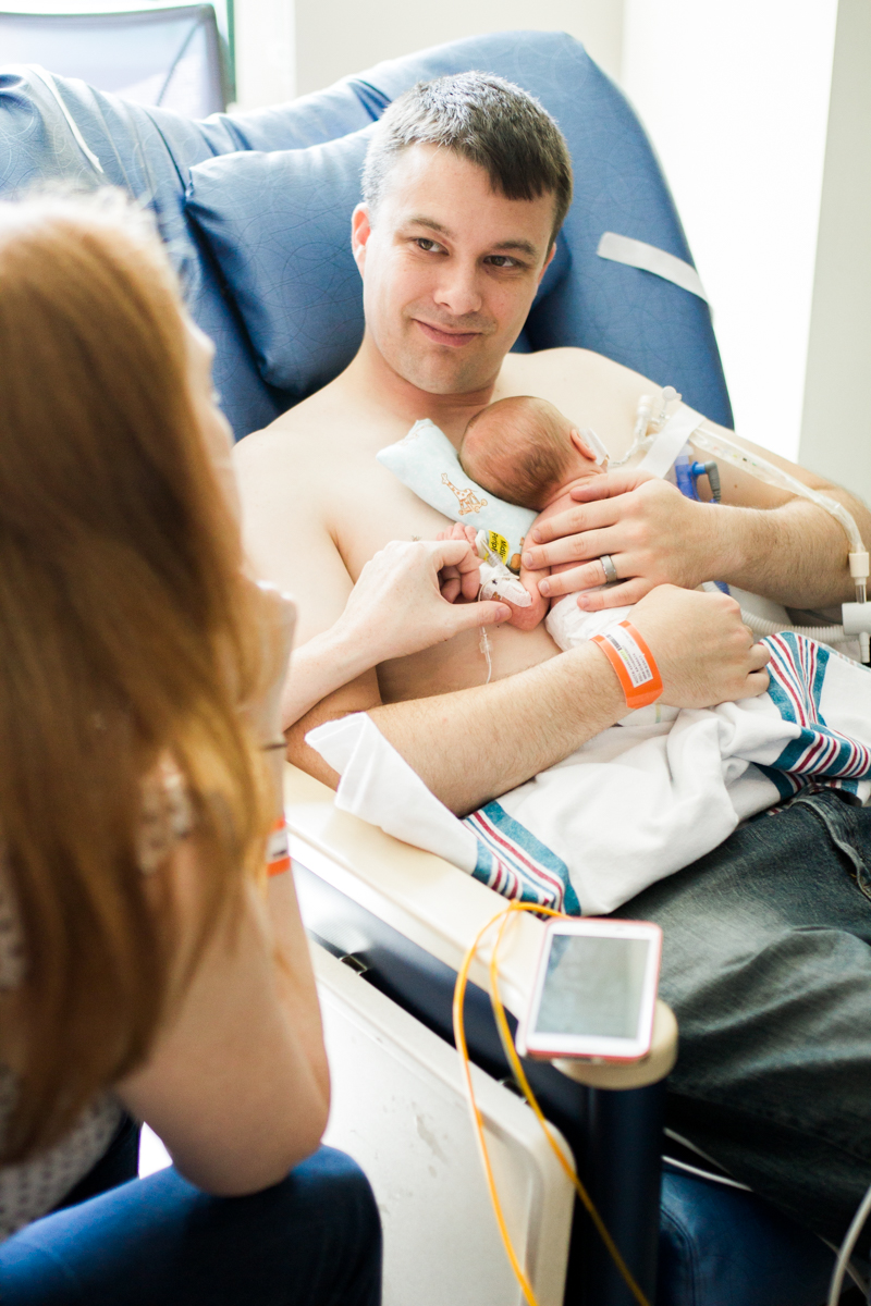  Rebecca Clair Photography lifestyle NICU newborn photography Children's Mercy Hospital father doing skin to skin with his baby mother holding baby's hand father looking at mother 