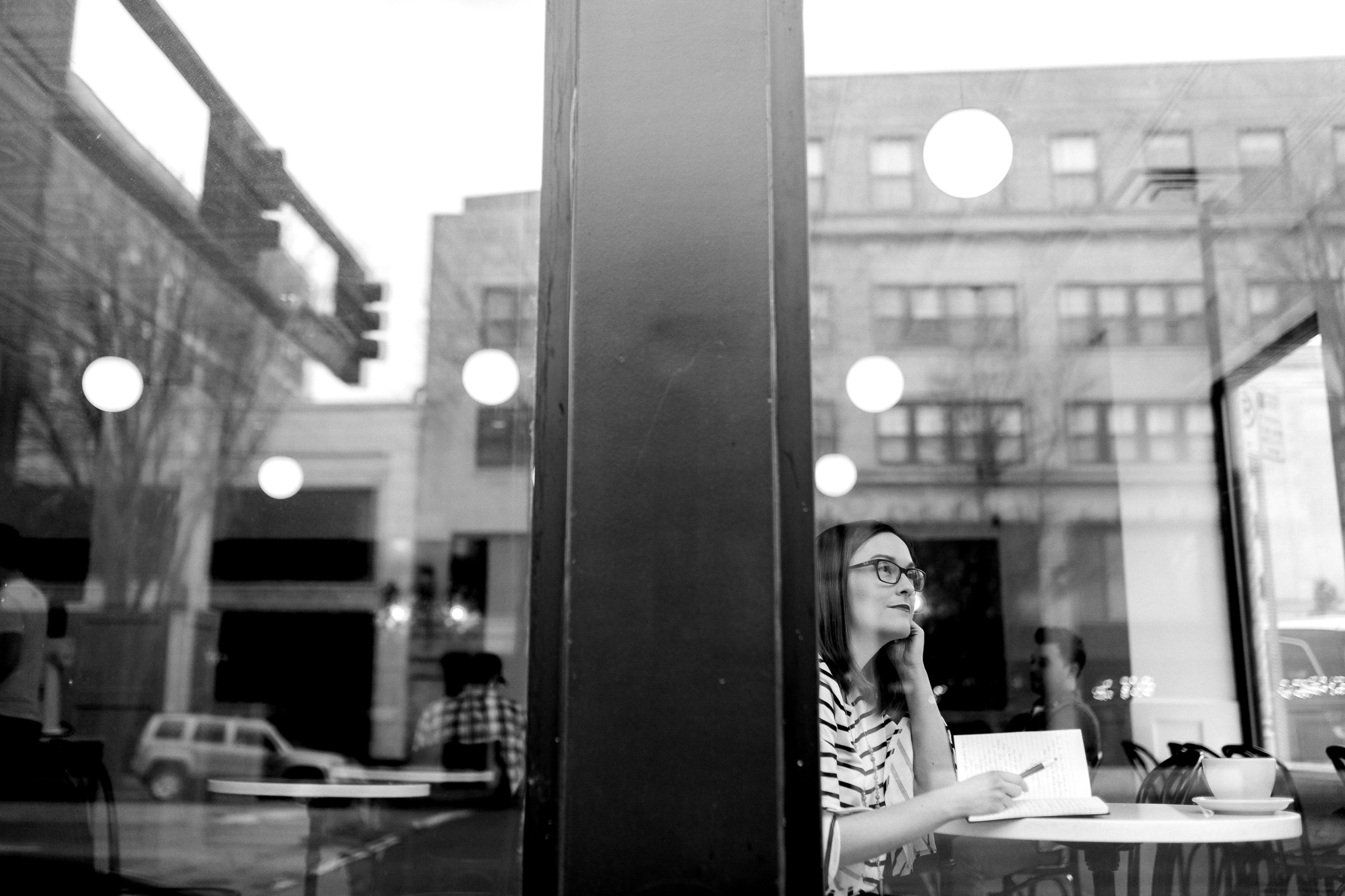  Black and white portrait of a woman thinking through the window of a coffee shop, Kansas City lifestyle photographer, Kansas City senior photographer, Kansas City small business headshots, Kansas City lifestyle blogger, candid portrait, winter portr