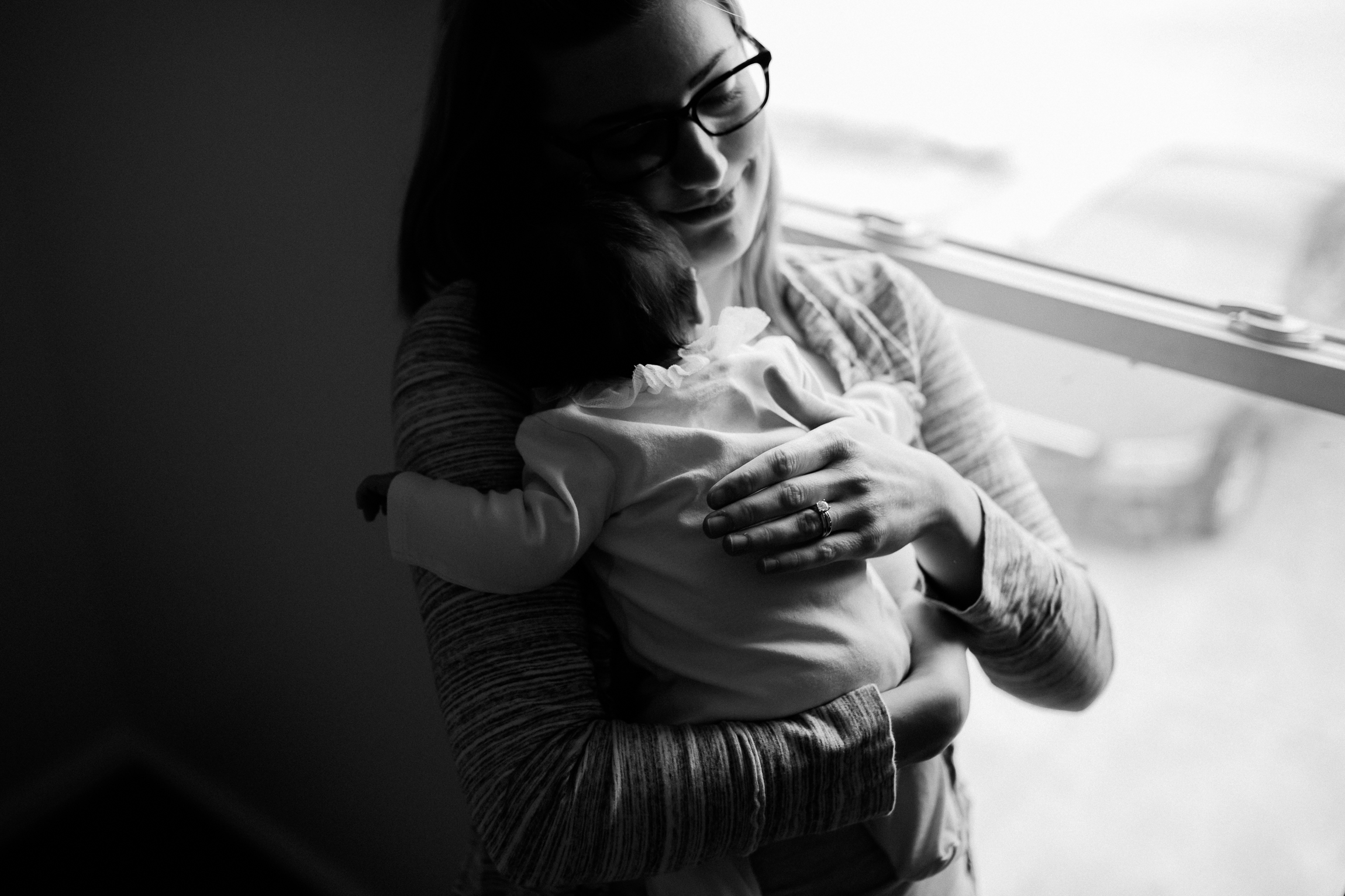  black and white portrait of mother holding newborn baby by the window, dramatic black and white portrait, Kansas City lifestyle newborn photographer, in-home newborn session 