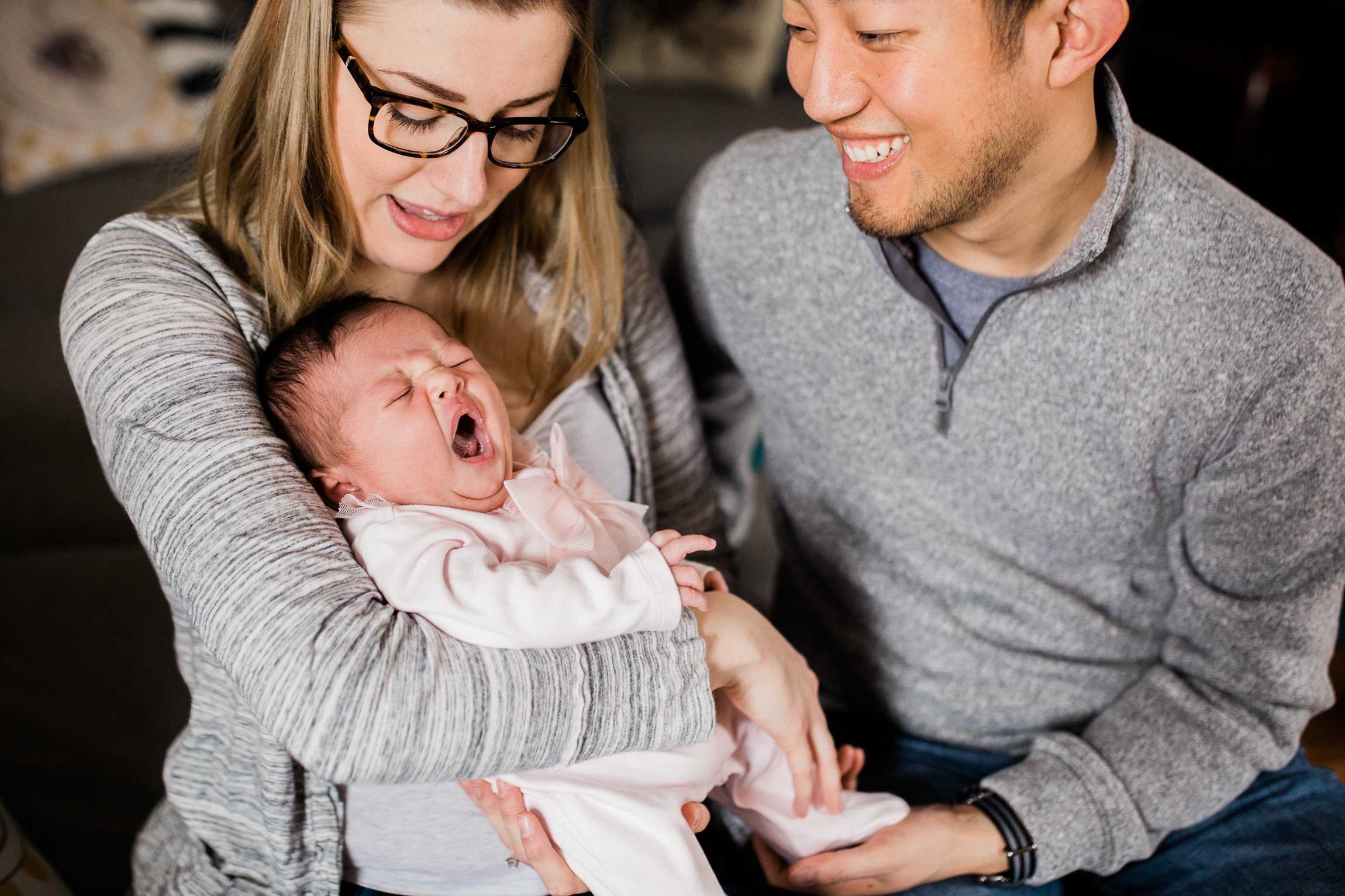  couple holding their newborn baby in the living room, newborn baby yawning, Kansas City lifestyle newborn photographer, in-home newborn session 