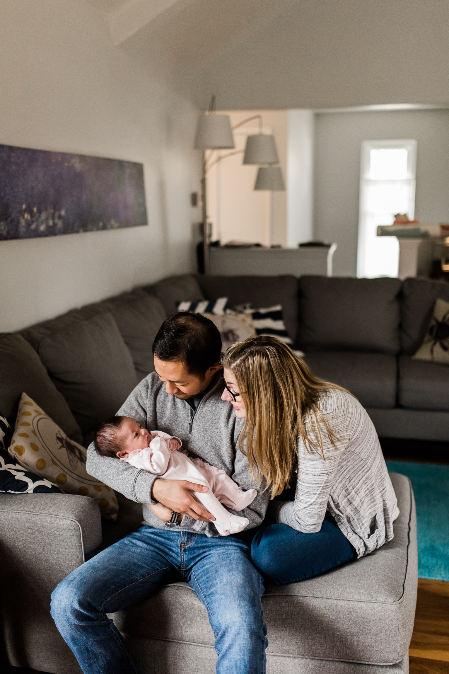  couple holding their newborn baby in the living room, Kansas City lifestyle newborn photographer, in-home newborn session 