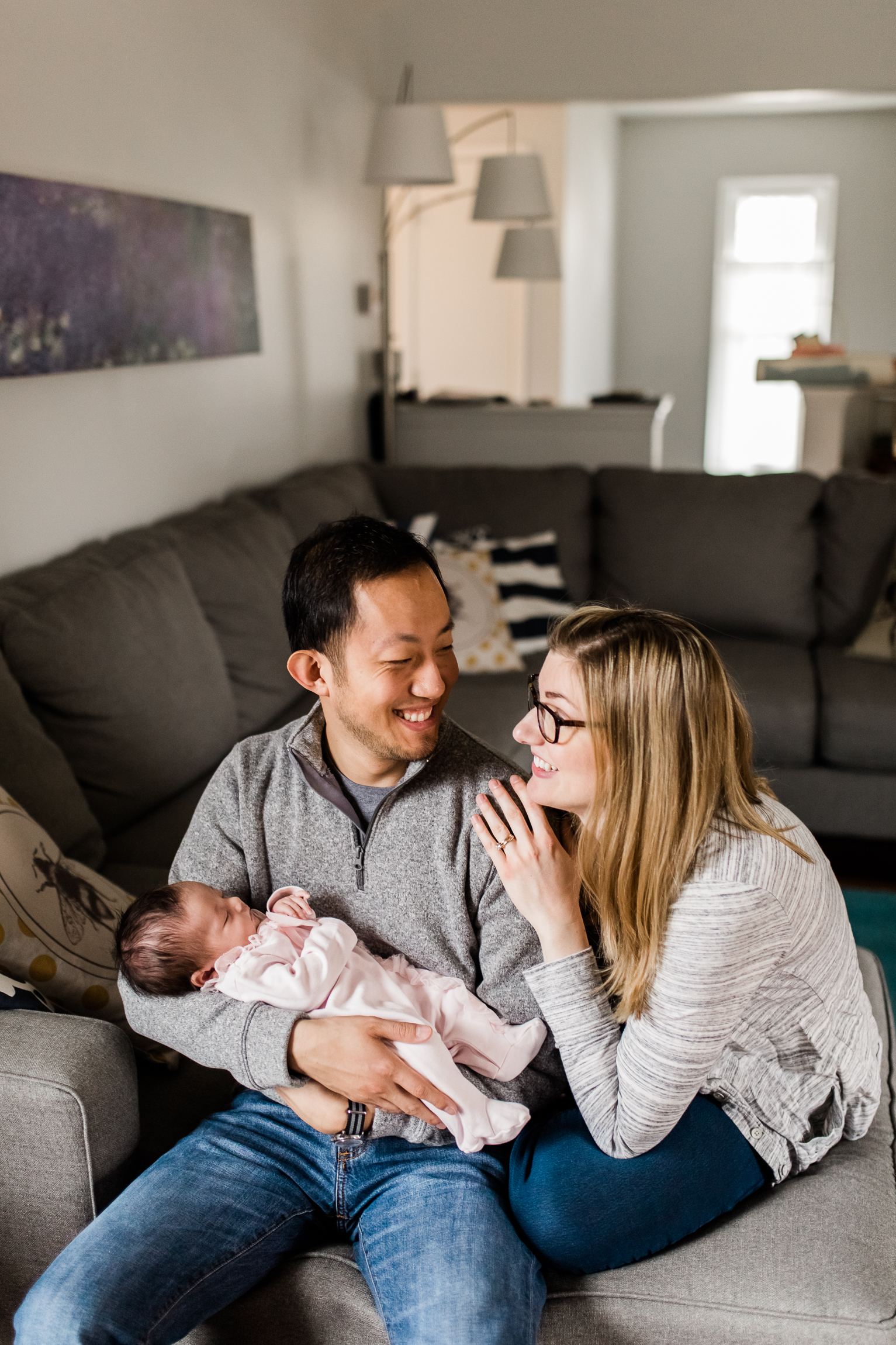  couple holding their newborn baby in the living room, parents looking at each other as they hold their newborn baby, Kansas City lifestyle newborn photographer, in-home newborn session 