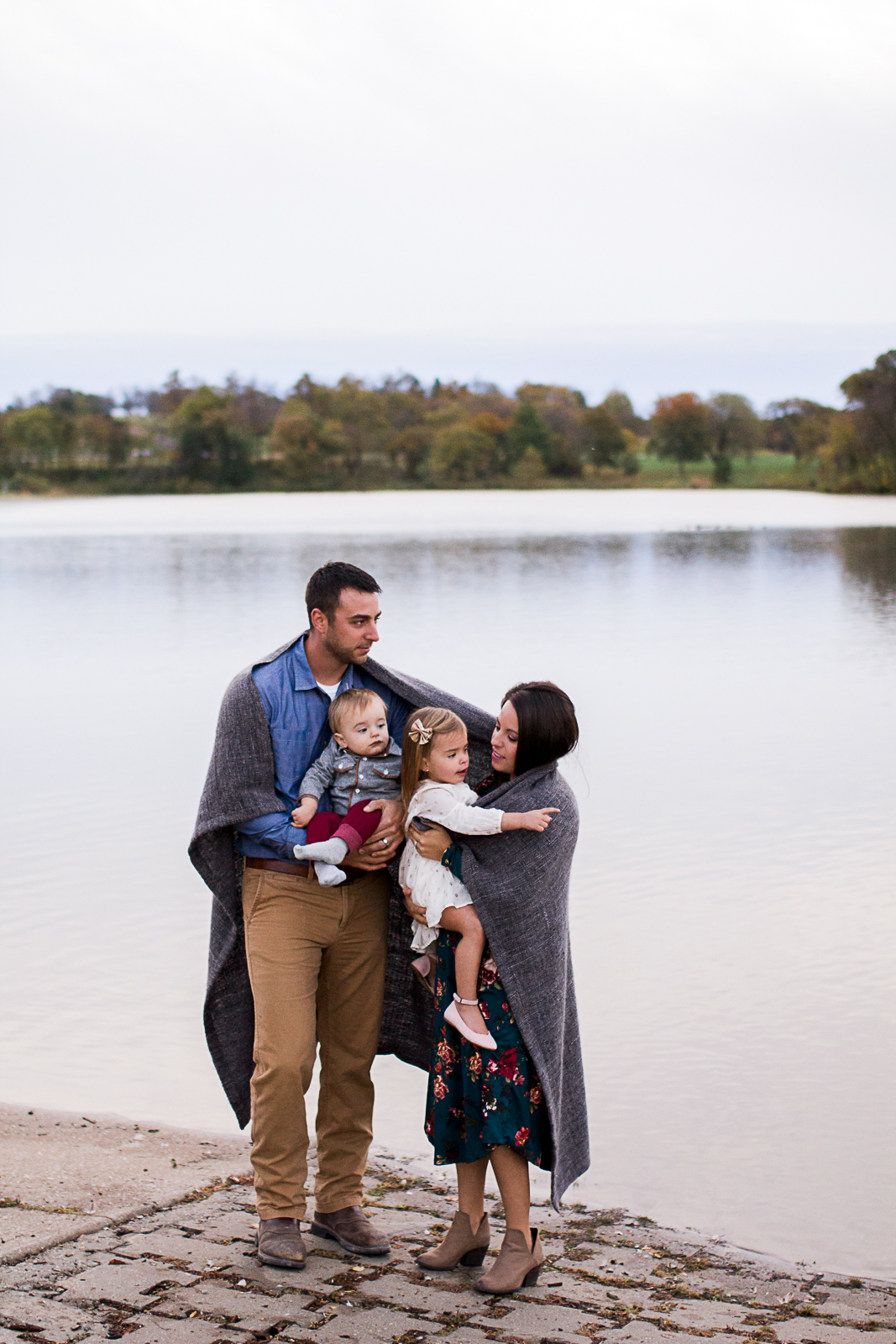  Family portrait wrapped in a blanket by the edge of the lake, sunrise family session at Shawnee Mission Park, Rebecca Clair Photography 