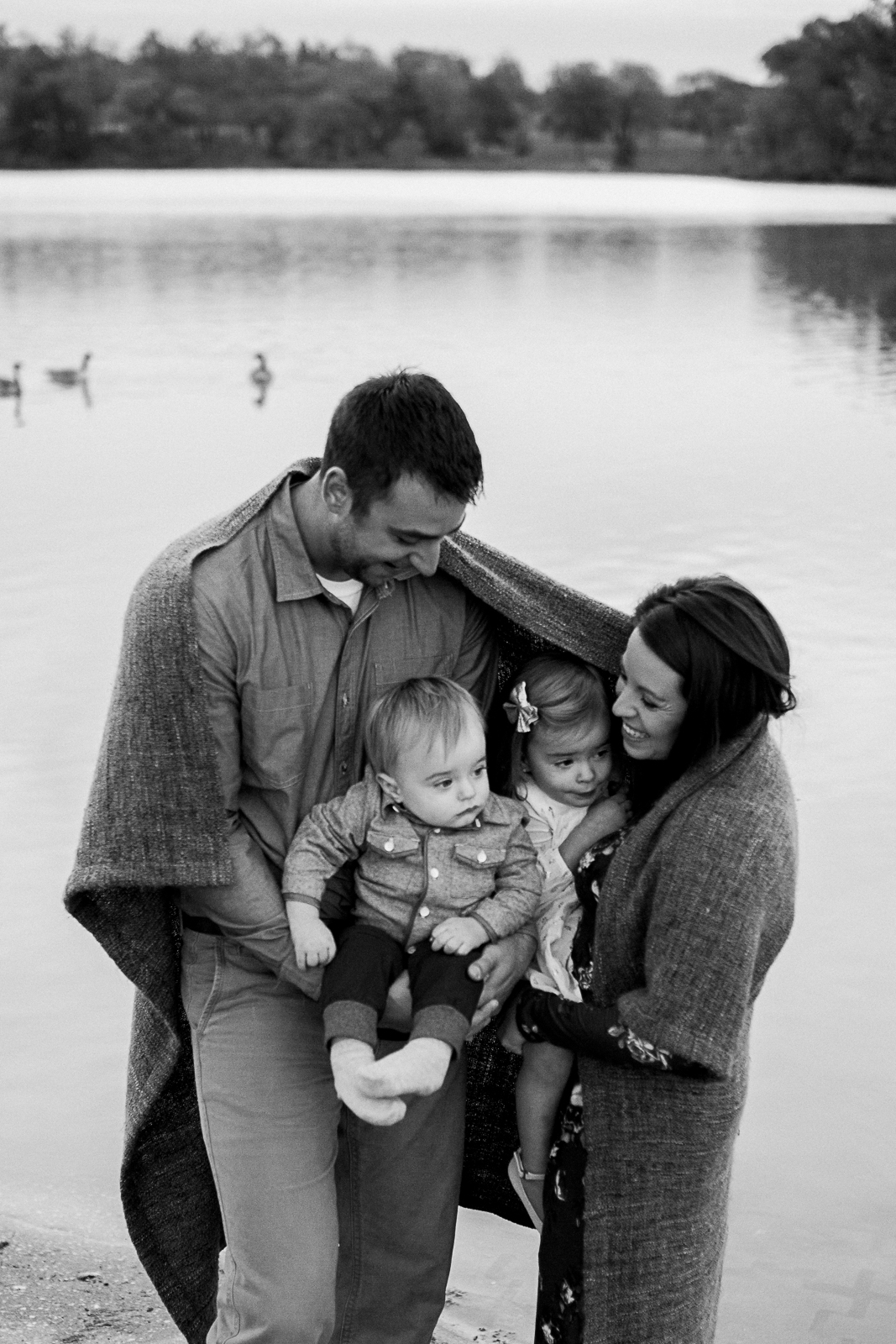  Candid black and white photo of family wrapped in a blanket, Kansas City family photographer, sunrise family session at Shawnee Mission Park, Rebecca Clair Photography 