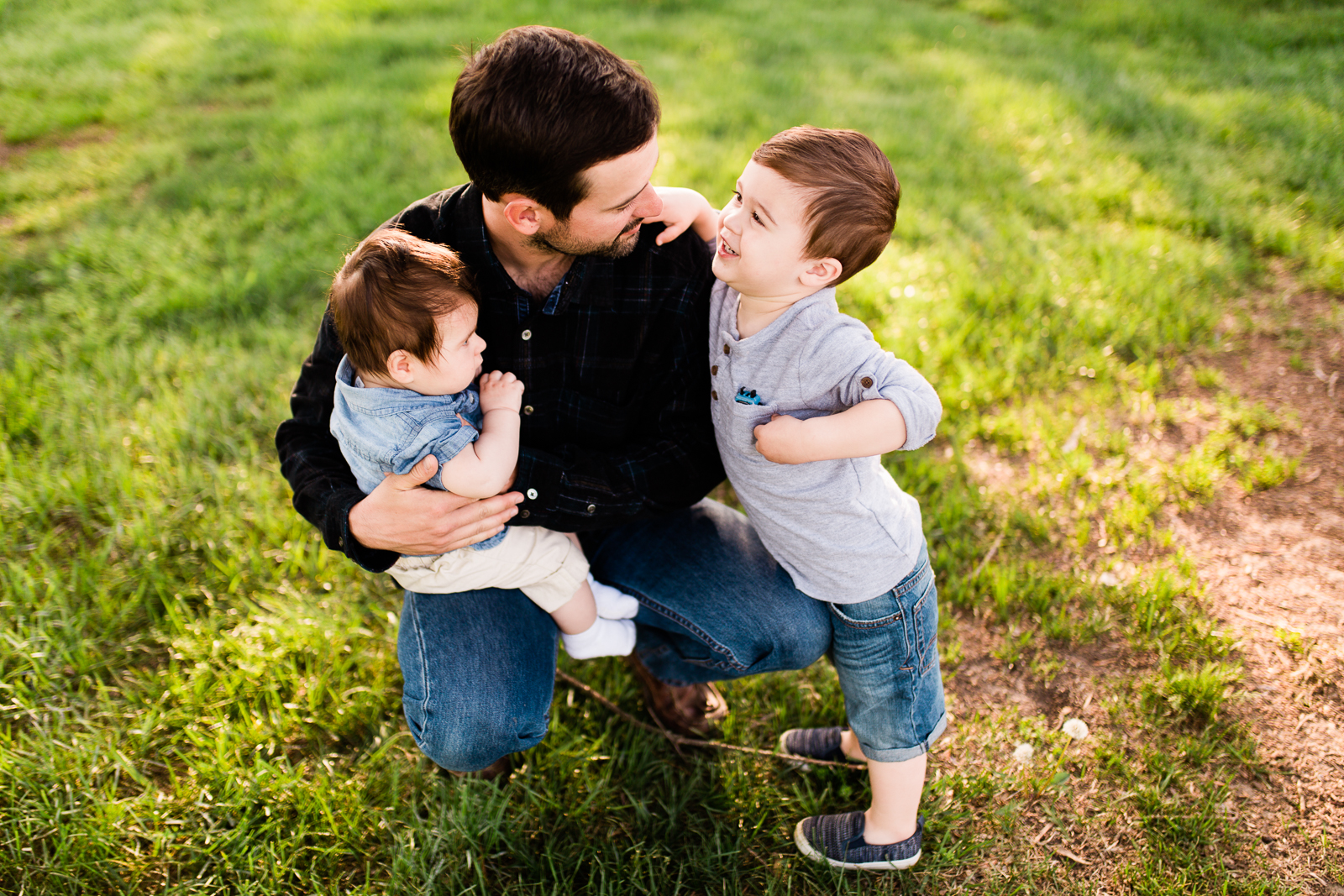  Father cuddles his sons in the evening light, Loose Park family session at golden hour, Kansas City lifestyle photographer, Rebecca Clair Photographer 