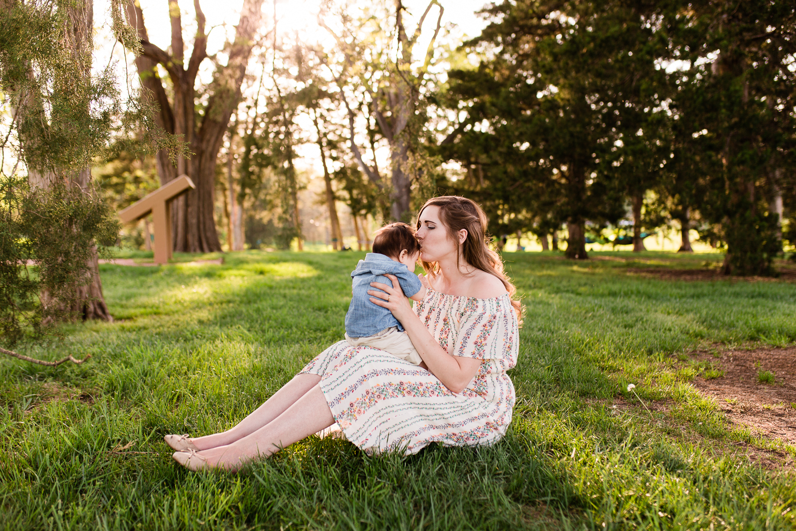  Mother kisses her son in a grove of trees, Loose park golden hour session, Kansas City family photographer, Rebecca Clair Photography 