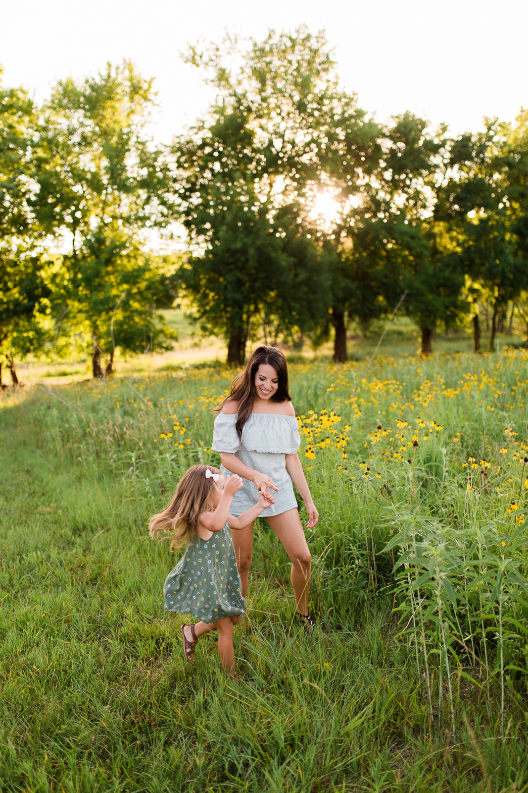  Mother dances with her daughter by a field of flowers, mommy and me session at Shawnee Mission Park, Kansas City family photographer 