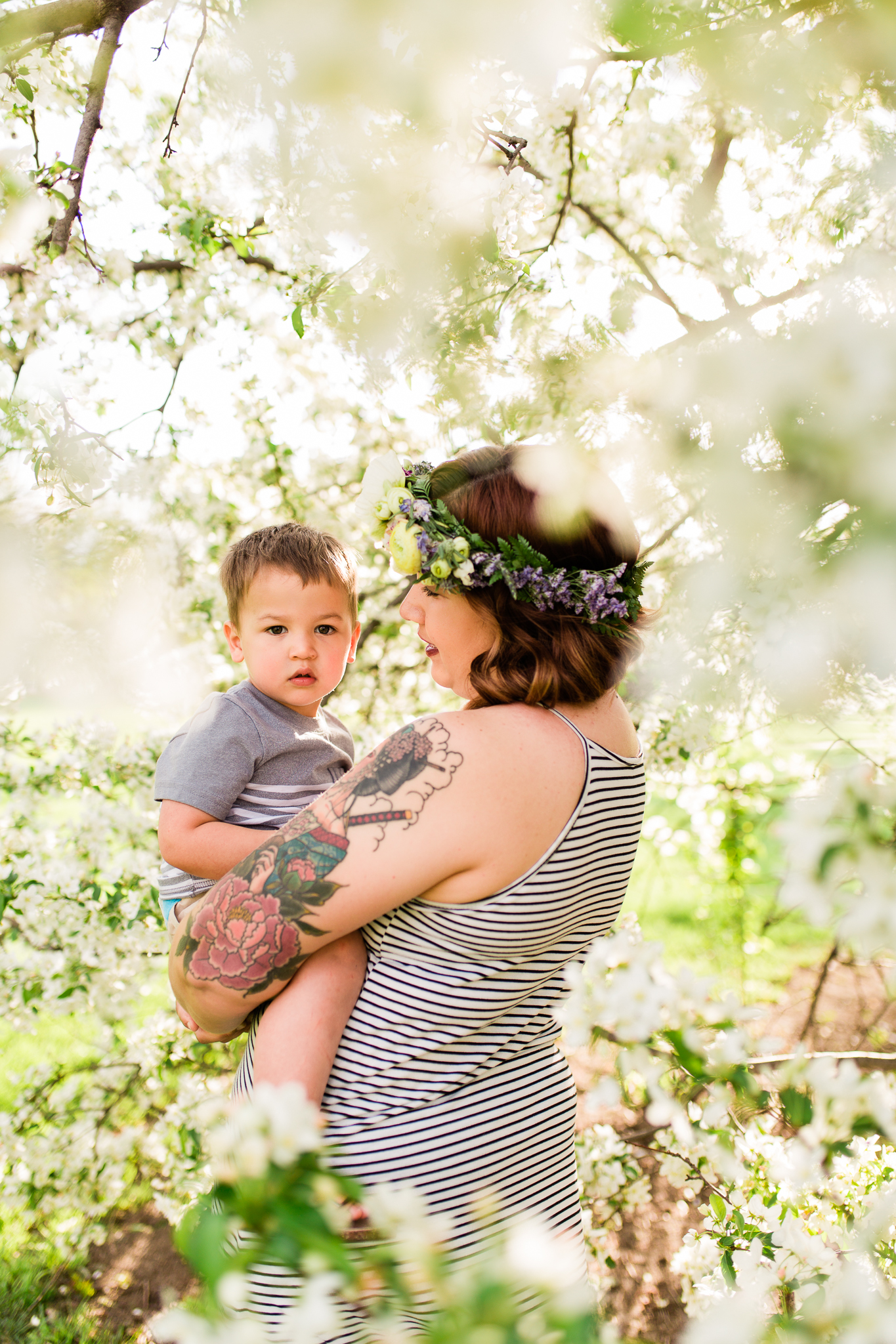 Mother holds her toddler son under a flowering apple tree, Kansas City mommy and me mini session, Loose Park in the spring, Rebecca Clair Photography