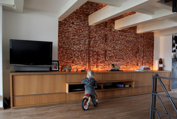 Brick wall illuminated from below by built in light fixtures placed behind furniture.