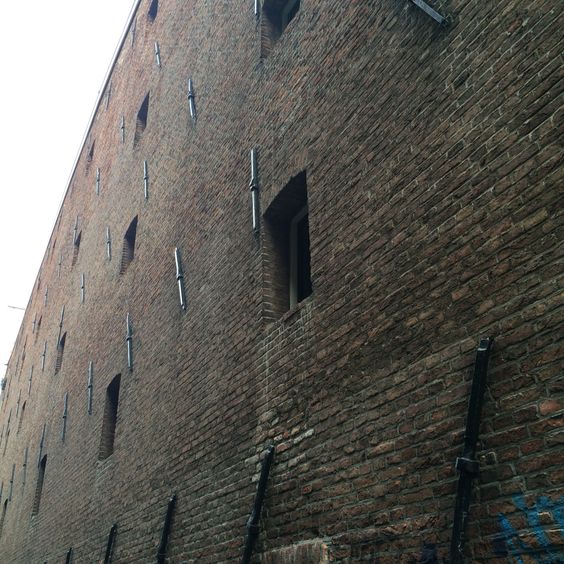 Side wall of the old warehouse building in Amsterdam. Sice it's construction it's been converted to loft apartments. Visible anchors holding wooden beams.