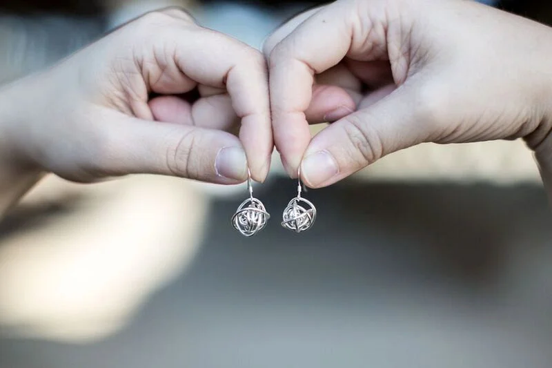 Antiqued sterling silver wrapped wire ball earrings on sterling silver earwires in hands