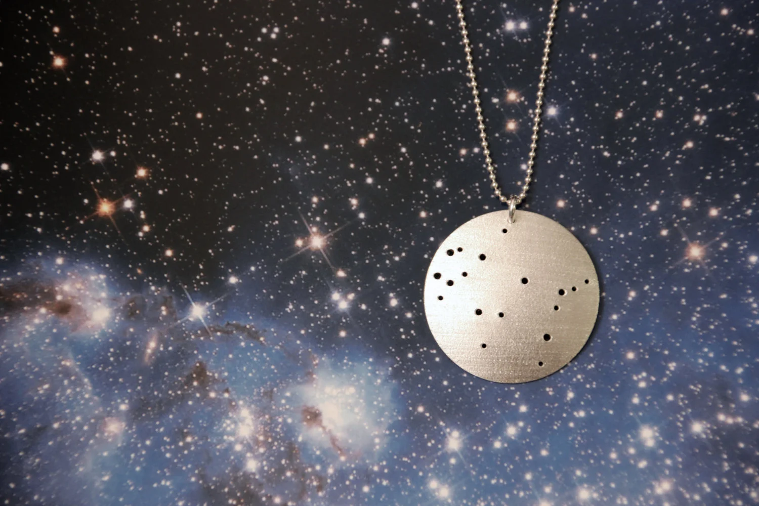 Round brushed silver pendant has 18 small holes drilled to match the Gemini constellation. Pendant is slightly domed and attached to a narrow silver ball chain with a silver jump ring.