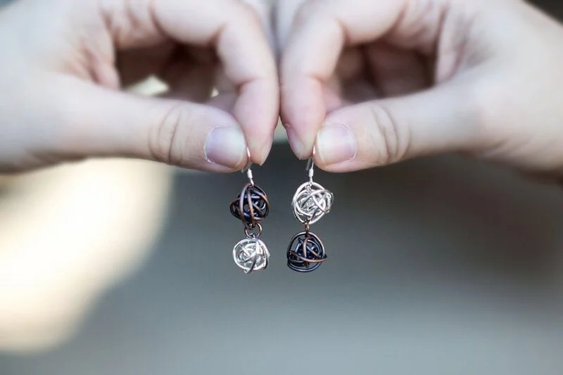 Antiqued copper and bright silver wrapped wire ball earrings on sterling silver earwires in hands